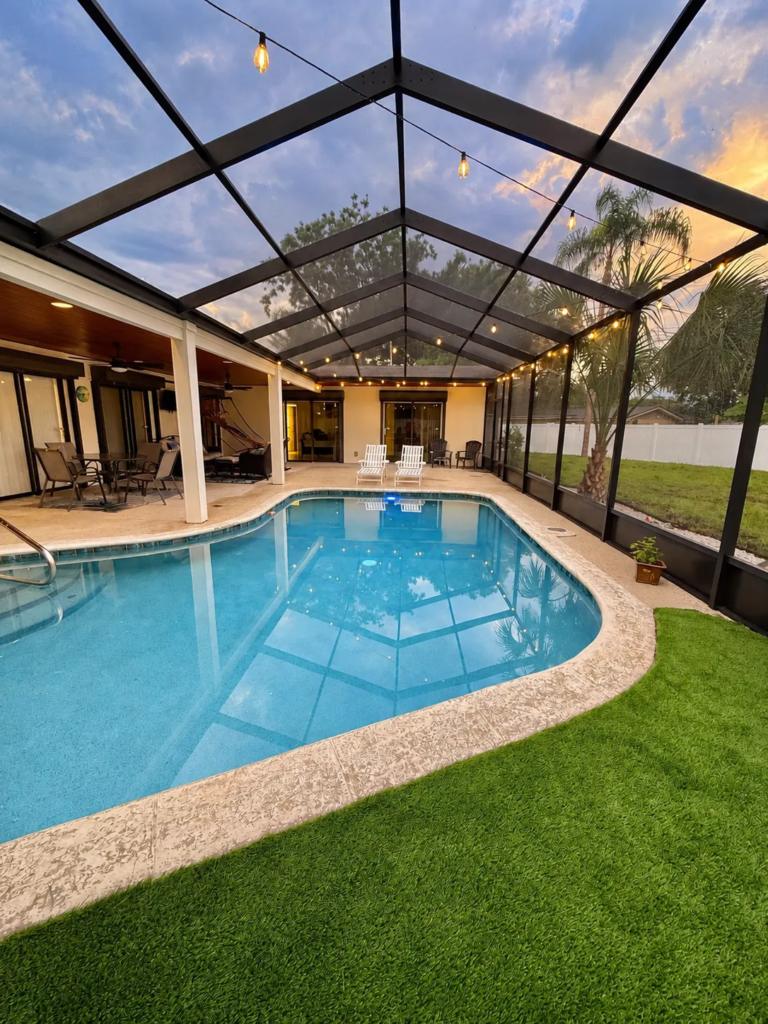 Screened pool at sunset with string lights and the covered lanai