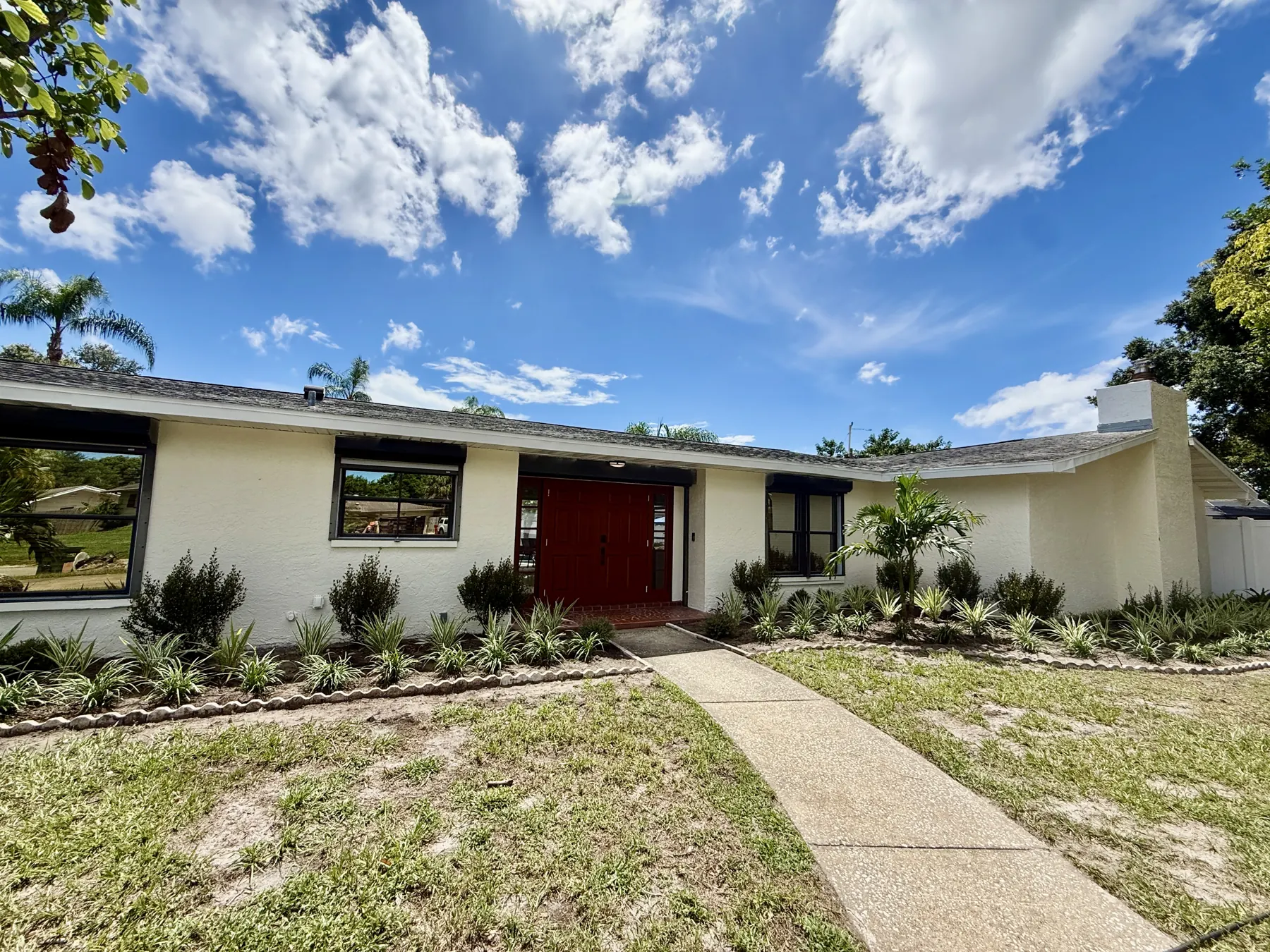 Front of the mid-century house with red double doors